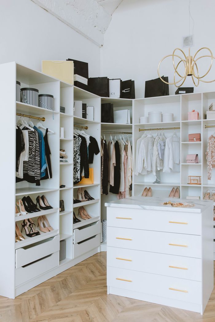 social-feed-img-02 A stylish walk-in closet featuring luxury clothing, shoes, and accessories, with elegant shelving and chandeliers.